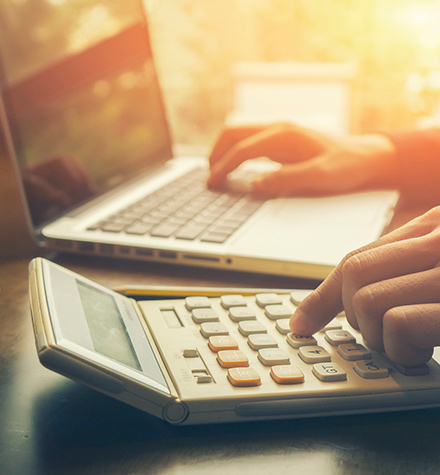 Person using a calculator and laptop.