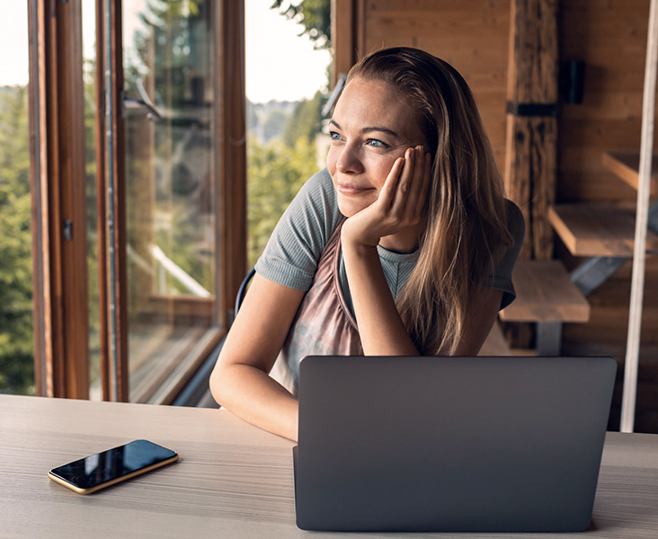 Person smiling in front of their laptop and phone.